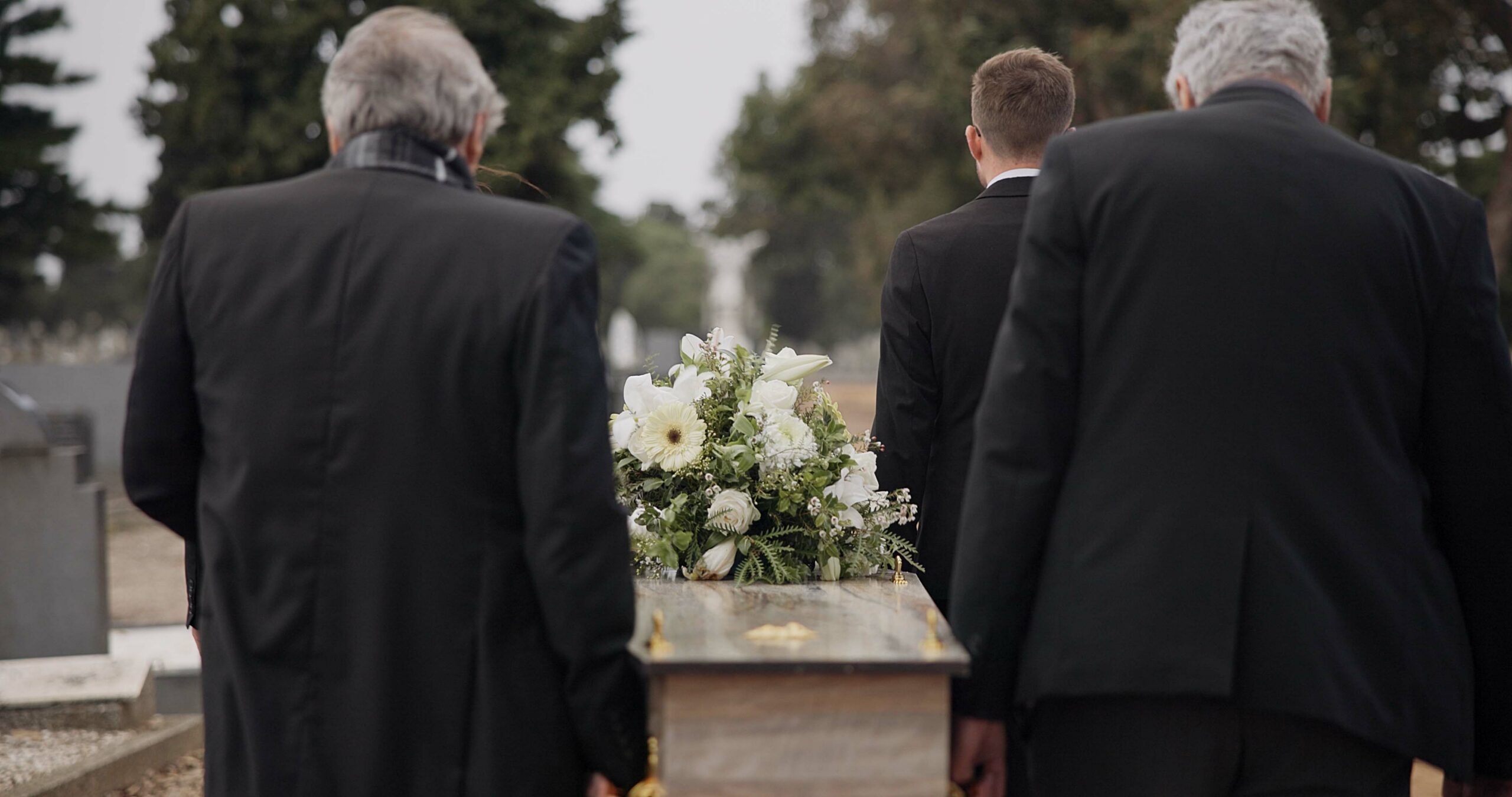 Men, coffin and pallbearers walking at cemetery ceremony outdoor at burial tomb. Death, grief and g.