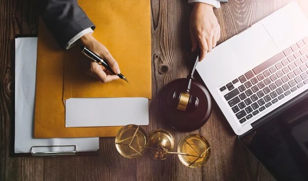 A lawyer with a laptop, gavel, scales, and legal documents gathering evidence for white collar crime defense.