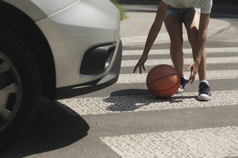 Child retrieving a basketball near a crosswalk moments before a potential pedestrian accident with an approaching vehicle in St. Louis.
