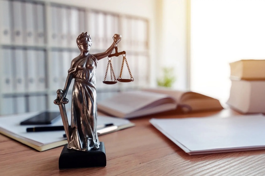 Lady Justice on a desk with legal books in the background.